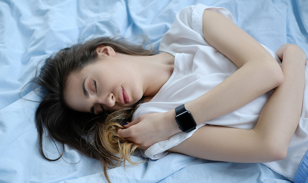 Young woman sleeping while wearing a smart watch